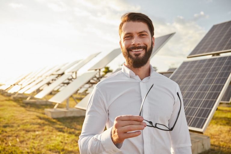 Homem branco em frente a painéis de produção de energia solar.